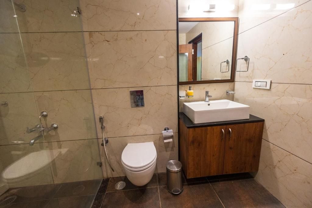Une salle de bain avec une douche à parois de verre, des toilettes blanches, un lavabo avec un meuble en bois et un miroir au-dessus du lavabo.