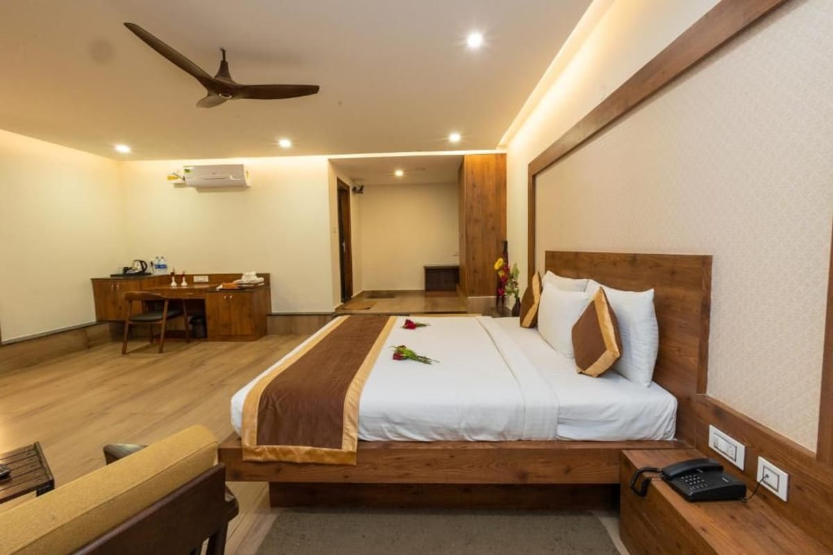 A hotel room with a bed, desk, chair, and a ceiling fan.