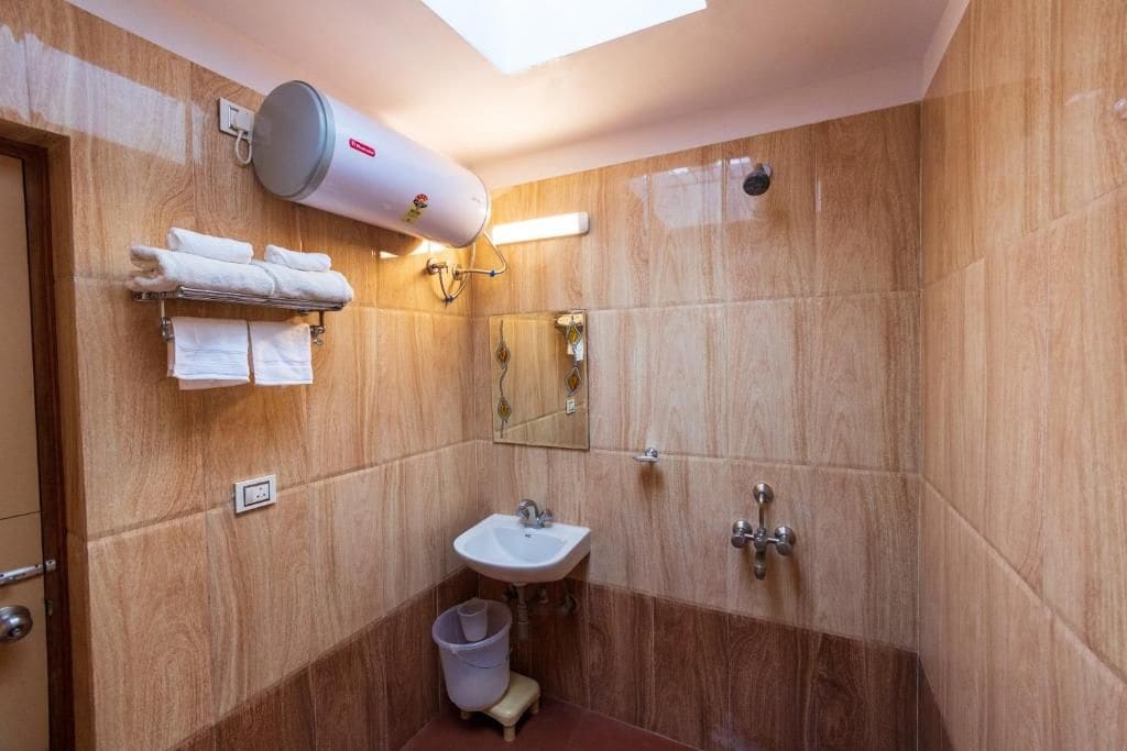 Une salle de bain équipée d’un porte-serviettes, d’un lavabo, d’un miroir et d’une douche.