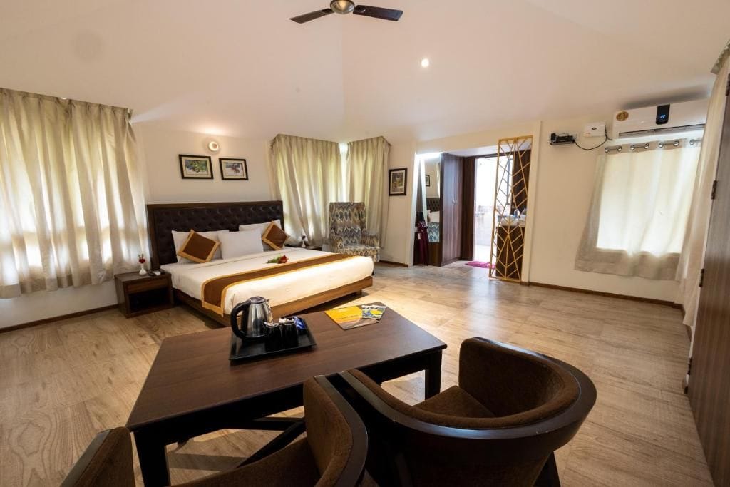 A hotel room with a bed, bedside table, chair, and a desk with a chair.