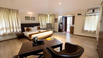 A hotel room with a bed, bedside table, chair, and a desk with a chair.