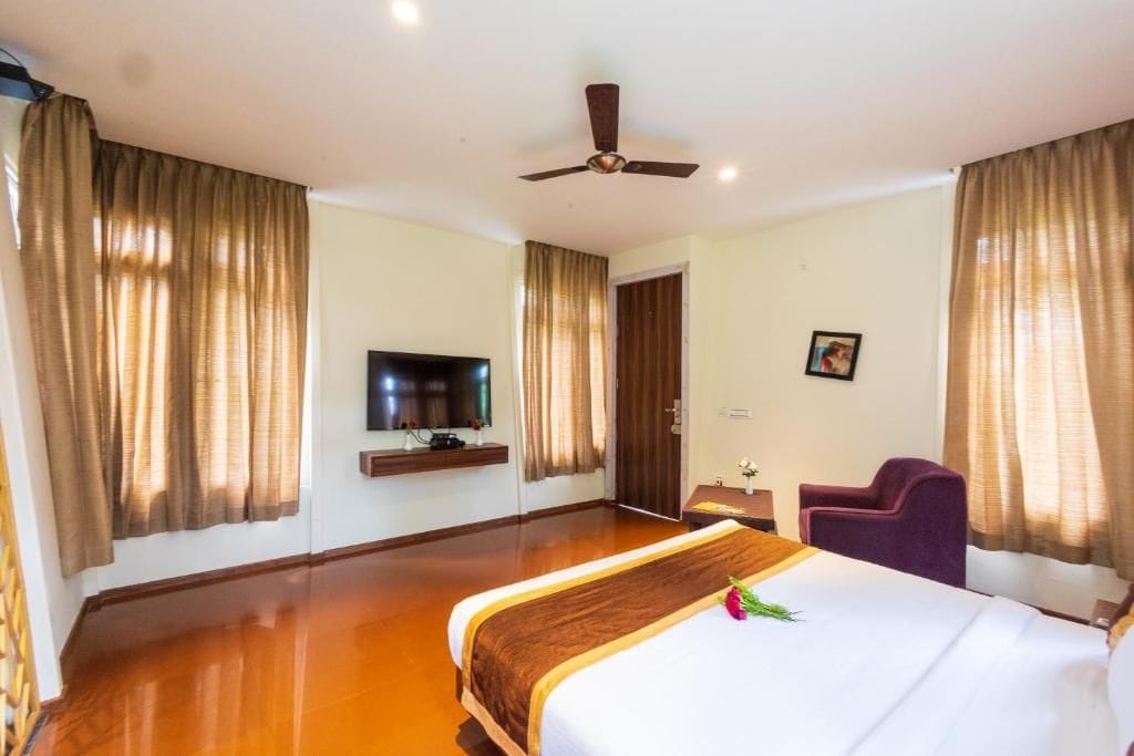 A hotel room with a bed, a television, a desk, and a chair.