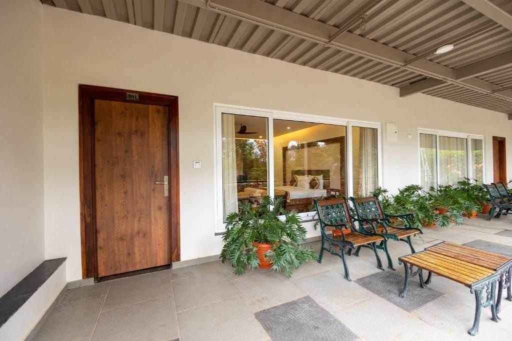 A hotel lobby with a wooden door, a seating area with chairs and a table, and potted plants.