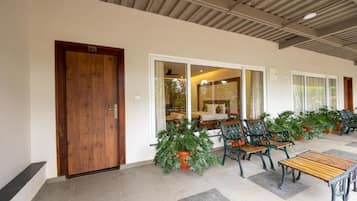 A hotel lobby with a wooden door, a seating area with chairs and a table, and potted plants.