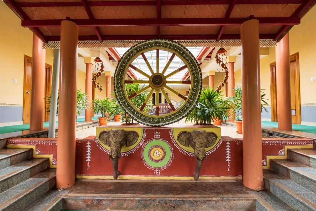 A traditional architectural structure with a large wheel, columns, and steps leading to a platform.