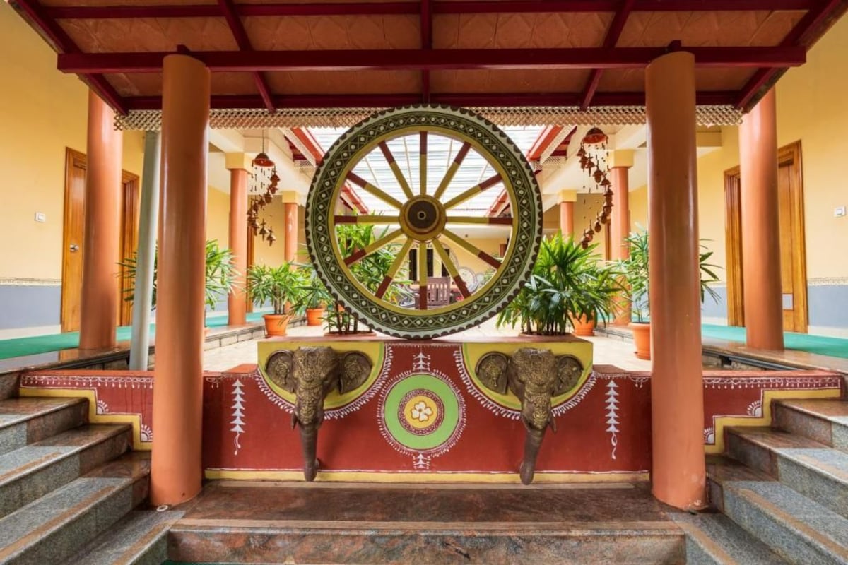 A traditional architectural structure with a large wheel, columns, and steps leading to a platform.