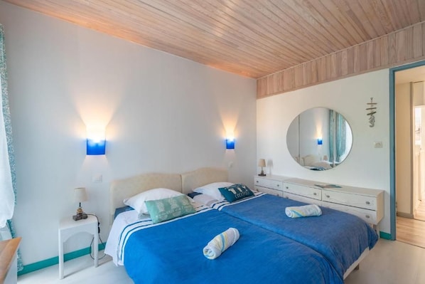 Ein Schlafzimmer mit einem Bett, Nachttischen, einem Spiegel und Wandleuchten.