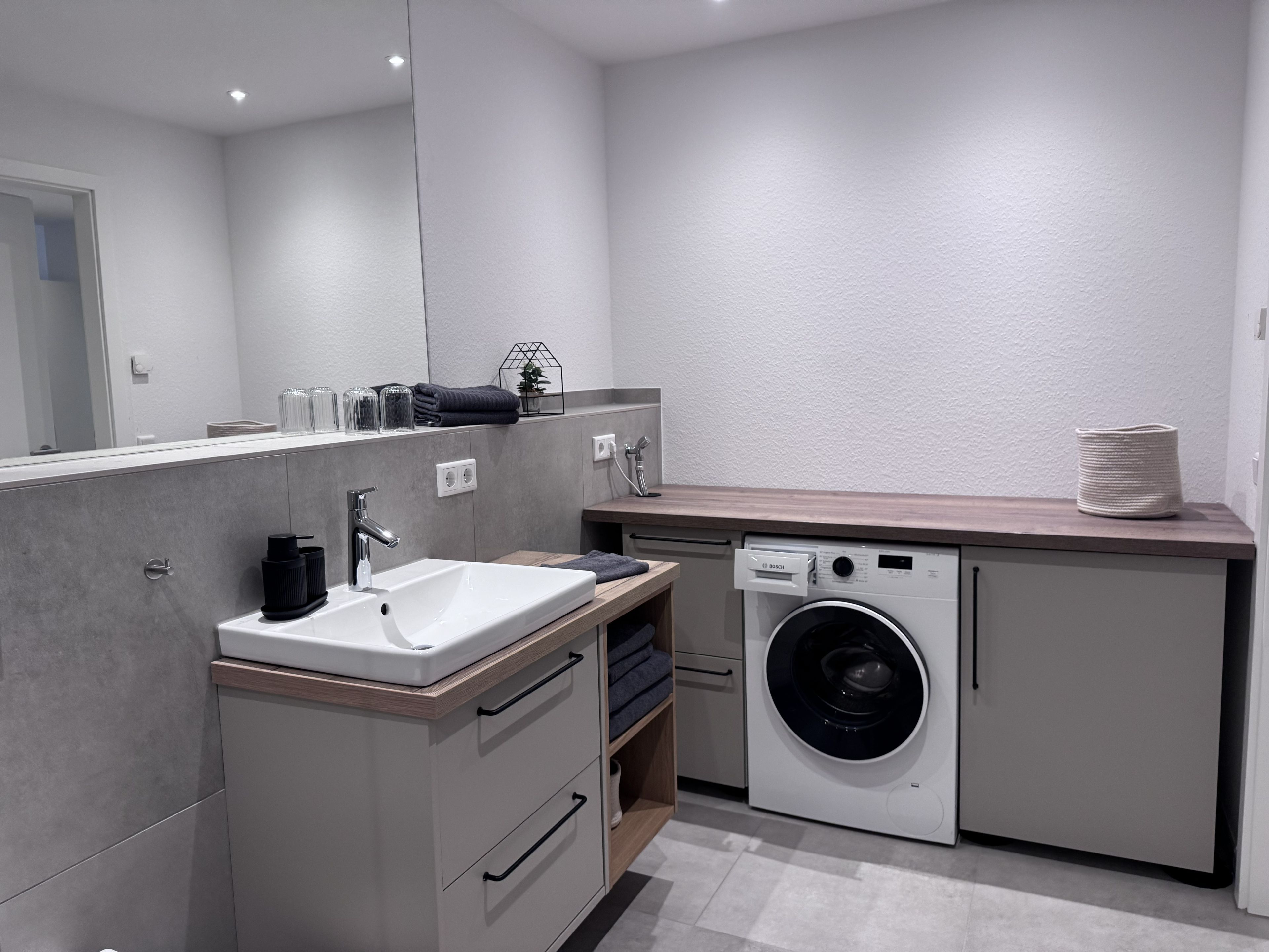 Une salle de bain moderne avec un lavabo, un miroir et un lave-linge.