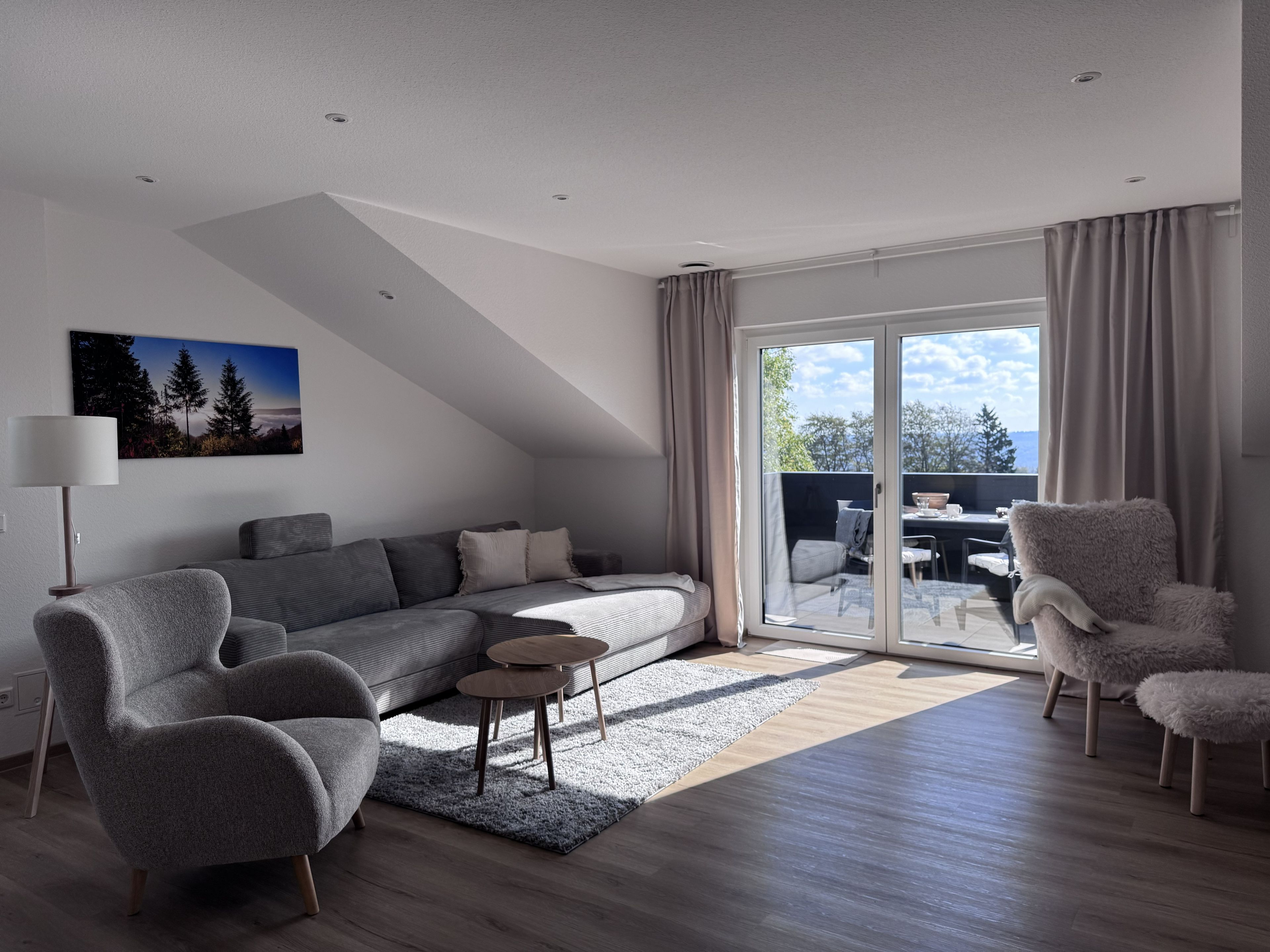 Ein modernes Wohnzimmer mit einer Couch, Sesseln, einem Couchtisch und einem Essbereich mit Tisch und Stühlen.