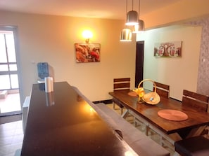 A dining area with a long table, chairs, and hanging pendant lights. - Marvelous 4-bedroom apartment in peaceful Nairobi, Kileleshwa neighborhood (Nairobi)