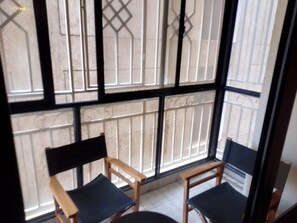 A room with two wooden chairs with black cushions, a small round table, and a large window with metal bars. - Marvelous 4-bedroom apartment in peaceful Nairobi, Kileleshwa neighborhood (Nairobi)