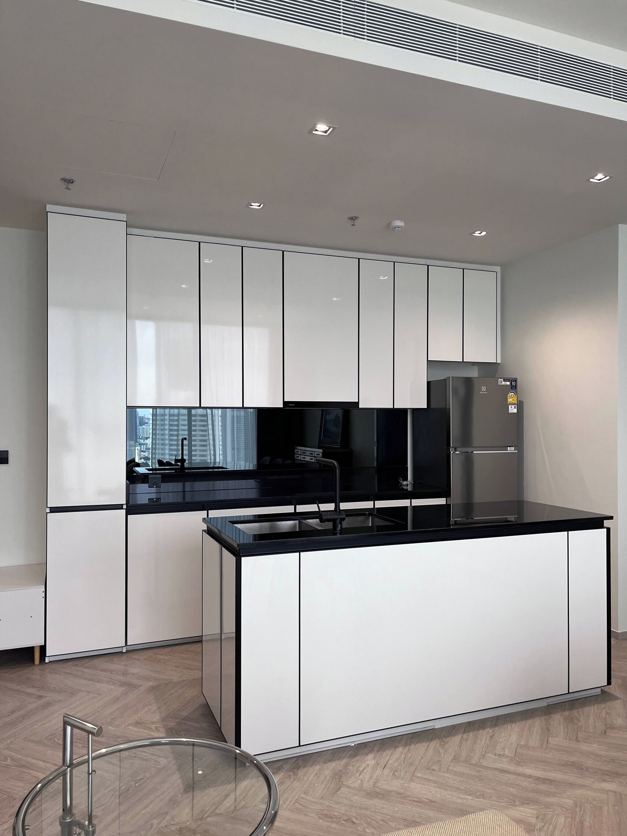 A modern kitchen with white cabinetry, a black countertop, and stainless steel appliances.