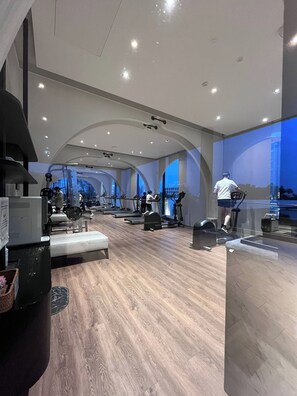A modern gym with multiple treadmills, stationary bikes, and weight machines. - Panoramic River View Condo, Long Stay (Khlong San)