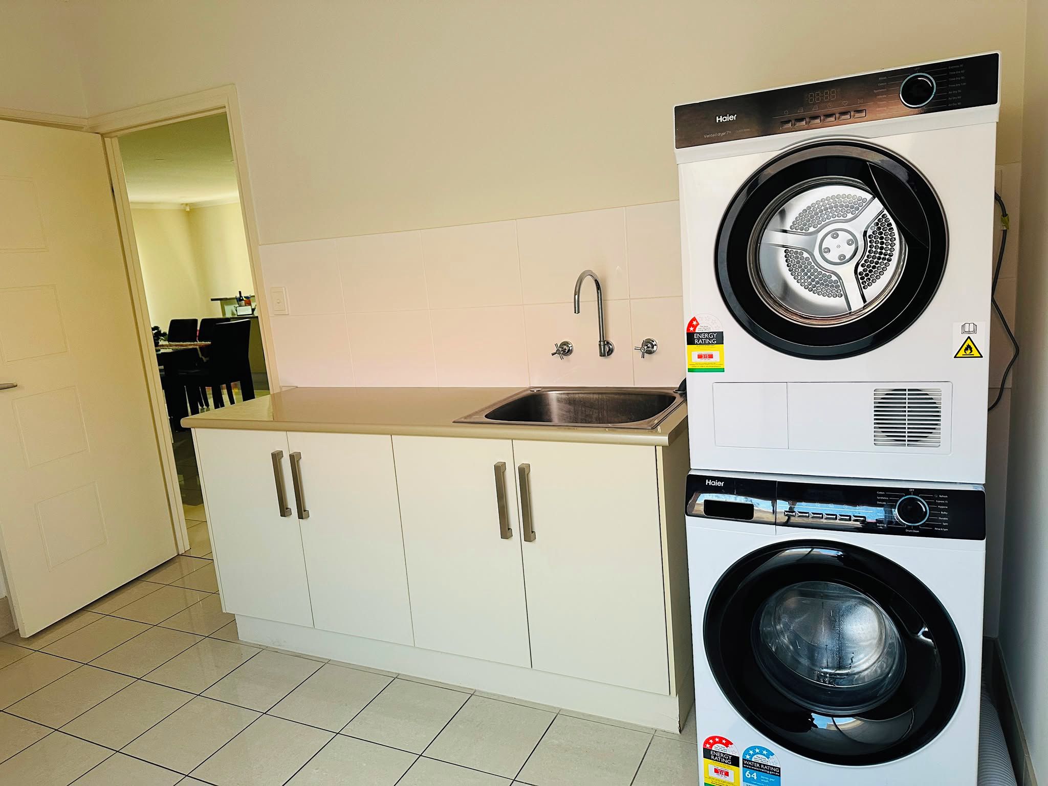 A compact kitchen with a built-in washer and dryer, a sink, and cabinets.