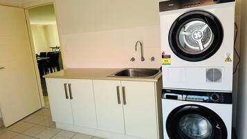 A compact kitchen with a built-in washer and dryer, a sink, and cabinets.