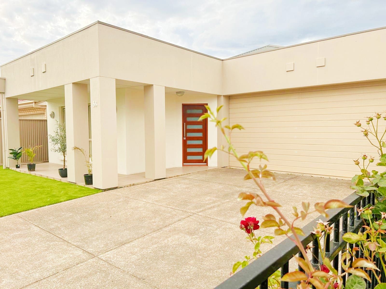 A modern building with a flat roof, a covered entrance, and a paved driveway.