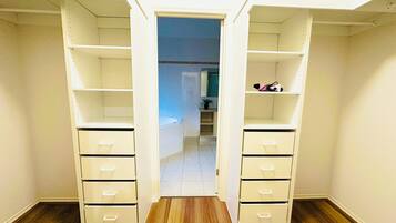 A walk-in closet with open shelving and drawers, leading to a bathroom.