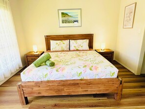 A wooden bed with a floral bedspread, two bedside lamps, and a painting on the wall. - Spacious 3BR, 2 Bath, Dbl garage, WIFI, Step-free (Athol Park)