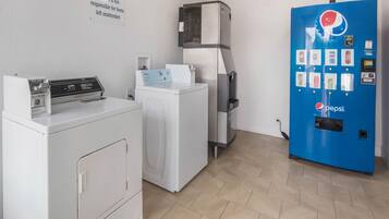 A laundry room with a white washer, dryer, and a blue vending machine.