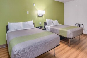 A hotel room with two beds, a bedside table with a phone, and a wall-mounted light fixture. - Comfy 2 Queen Beds | Nsmk, Micfridge (Remote City USA)