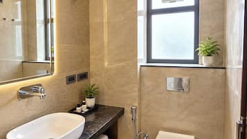 A modern bathroom with a large mirror, a white sink, a toilet, and a shower.