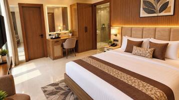Quarto de hotel com uma cama grande, uma escrivaninha, uma cadeira, um espelho e zona de chuveiro.
