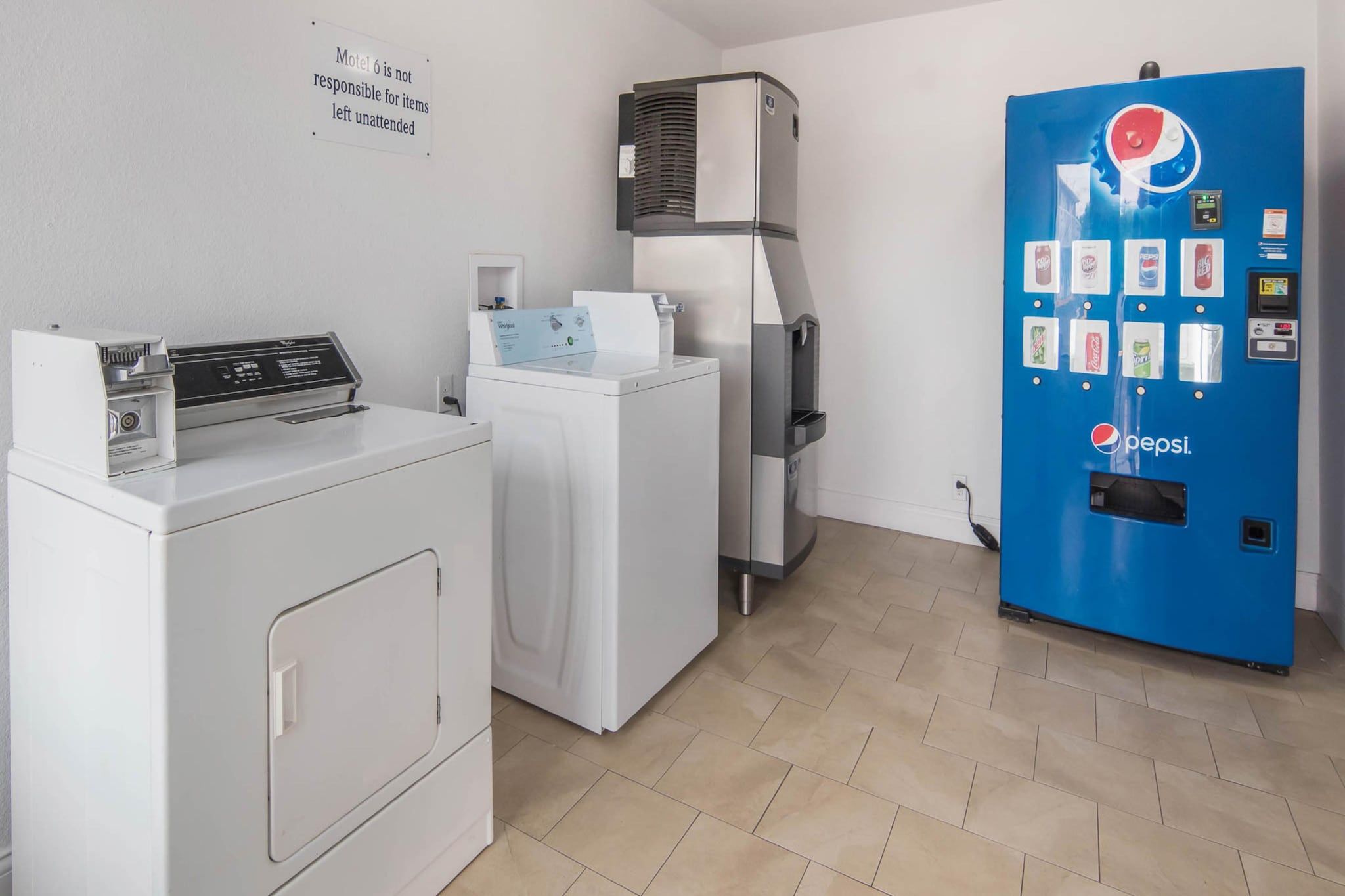 Een wasserette met een witte wasmachine, droger en een blauwe automaat.