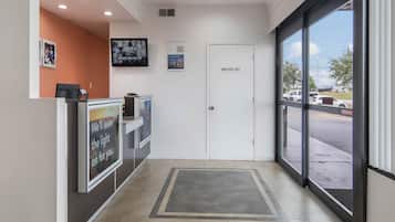 A reception area with a closed door labeled 'EMPLOYEES ONLY,' a counter with a sign saying 'We'll leave the light on for you,' and a television mounted on the wall.