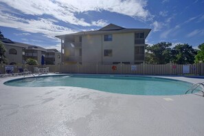 A swimming pool with a wooden fence, a lifeguard chair, and a sign indicating shallow water. - Beach Days + Hot Tub Nights: Little River Condo (Little River)