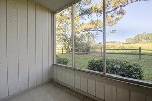 A room with a large window overlooking a grassy area with trees and a fence. - Beach Days + Hot Tub Nights: Little River Condo (Little River)