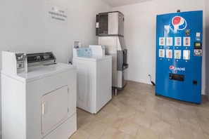 A laundry area with a white washer, dryer, and a blue vending machine. - 1 King Bed Mob Acc Tub Nsmk Micfridg (Remote City USA)