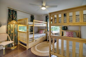 A bunk bed room with a ceiling fan, a chair, and a window with curtains. - Oceanfront Gem! Steps to Sand, Miles from Ordinary (Vero Beach)