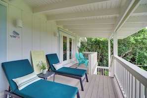 A covered porch with two lounge chairs and a small table, a sign prohibiting smoking and vaping, and a view of greenery. - Oceanfront Gem! Steps to Sand, Miles from Ordinary (Vero Beach)