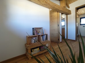 A room with a wooden bookshelf, a door leading to another room, and a plant in the foreground. - The Charming Sicarderie Guesthouse, 30 minutes from Bordeaux (Peujard)