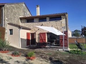 A house with a stone facade, a chimney, and a patio with outdoor furniture. - The Charming Sicarderie Guesthouse, 30 minutes from Bordeaux (Peujard)