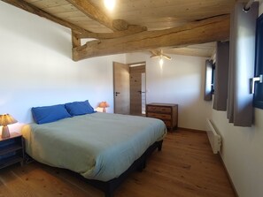 A bedroom with a bed, bedside lamp, wooden dresser, and a ceiling fan. - The Charming Sicarderie Guesthouse, 30 minutes from Bordeaux (Peujard)