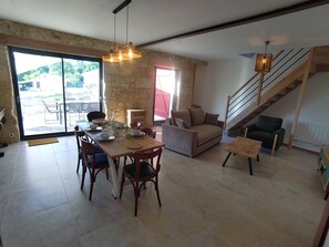 A spacious living area with a dining table set for four, a sofa, a staircase, and a view of the outdoors. - The Charming Sicarderie Guesthouse, 30 minutes from Bordeaux (Peujard)