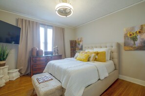 A bedroom with a bed, a dresser, a television, and a painting. - Midtown Memphis Home w/ Home Gym & Office (Memphis)
