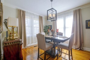 A dining room with a wooden table, chairs, a chandelier, and curtains. - Midtown Memphis Home w/ Home Gym & Office (Memphis)