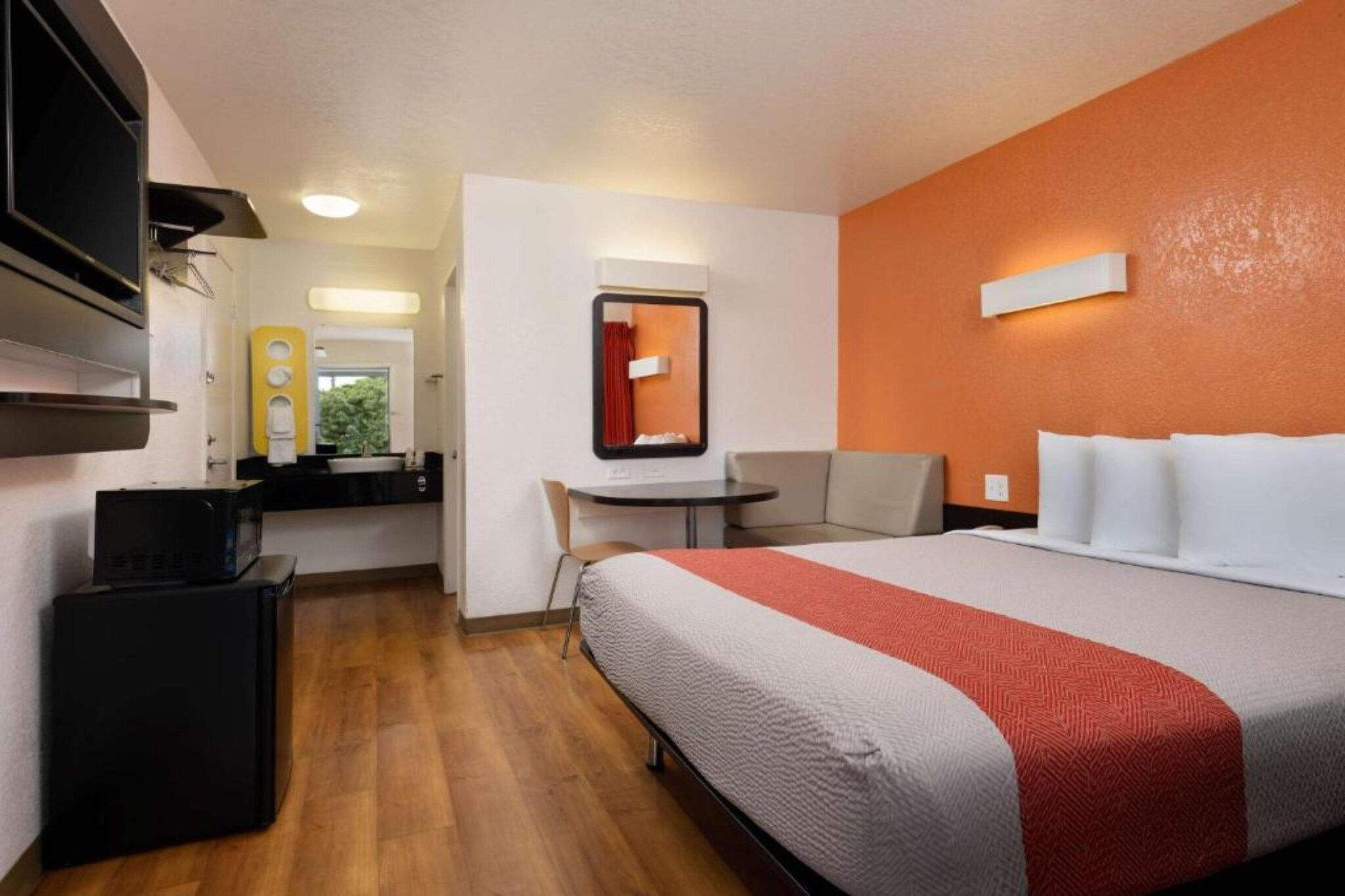 A hotel room with a bed, a desk, a chair, and a television.