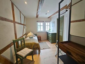 Une chambre à coucher avec un lit, une chaise, une commode et une fenêtre.