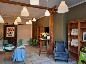 Une pièce avec une table en bois, des chaises, un fauteuil bleu et une bibliothèque avec des photos encadrées.