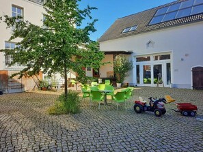 A courtyard with cobblestone flooring, outdoor seating, and a toy tractor. - defaultName (Werdau)