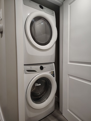 A compact, two-door laundry room with a built-in washer and dryer. - Cozy 3-Bedroom House Rental in Calgary's Rosscarrock Area (Calgary)