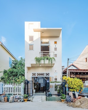 A two-story building with a flat roof, a gated entrance, and a balcony with hanging plants. - Laoxao Memories (Đà Nẵng)