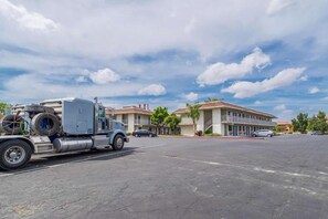 Un parking avec un grand camion et un immeuble doté de nombreux balcons.