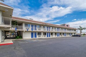Ein Motel mit mehreren Zimmern, einem Parkplatz und blauem Himmel.