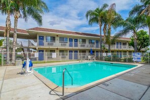 Ein Hotel mit Schwimmbad, mehreren Balkonen und Palmen.