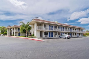 A two-story motel with a parking lot and a single car parked in front. - 1 Full Bed | Mobility Access Tub, Nsmk (Bakersfield)