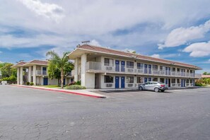 A two-story motel with a parking lot and a single car parked in front. - 2 Full Beds | Non-Smoking (Bakersfield)